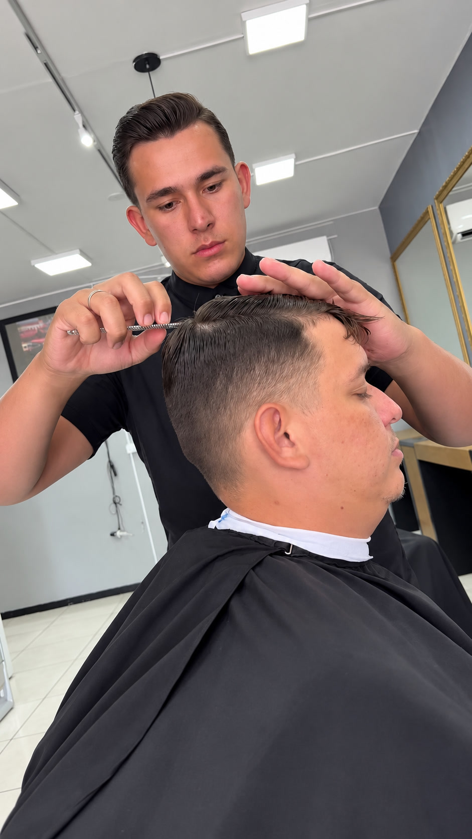 Barbeiro trabalhando no corte de um cliente